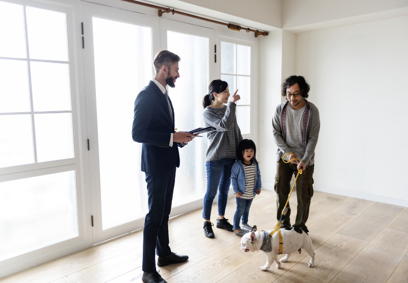 A family with their dog and a real estate agent checking a house